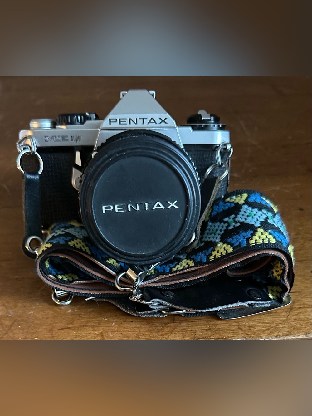 Pentax Silver and Black SLR Camera with Black Lens Cap and Colorful Strap